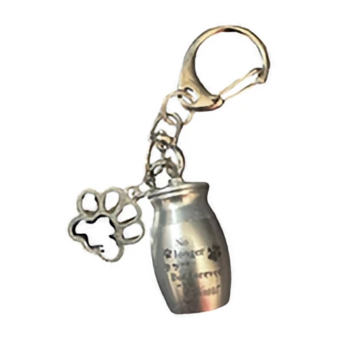 A silver keychain attached to a small cremation urn charm and a dangling pet paw print charm.